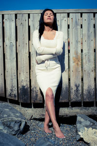 Woman with eyes closed standing against fence