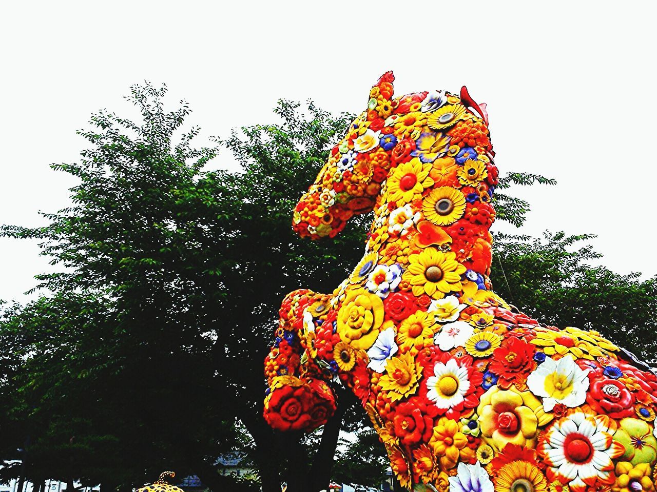 low angle view, art and craft, art, clear sky, tree, creativity, human representation, tradition, multi colored, cultures, sculpture, celebration, decoration, sky, statue, religion, animal representation, spirituality