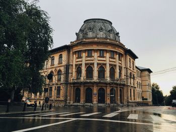 Exterior of carol i national college by wet road against clear sky