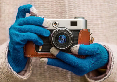 Close up of woman hands in warm gloves holding retro photo camera