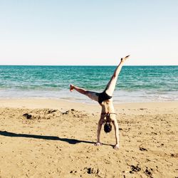 Full length of woman walking on beach against clear sky