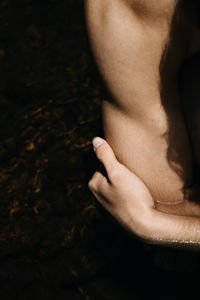 Close-up of hands hugging arm on dark background