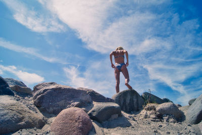 Woman standing on rock against sky