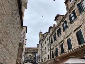Low angle view of buildings in dubrovnik with birds in the sky