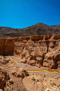 Rock formations on mountain against clear blue sky