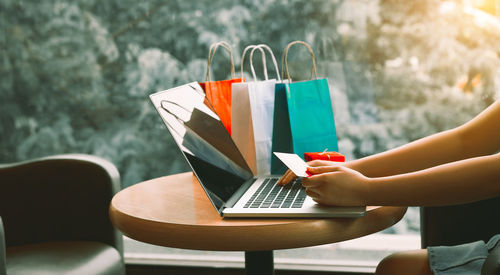 Cropped image of woman online shopping using laptop at table