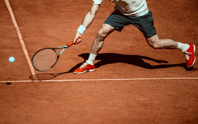 Low section of man playing tennis in court