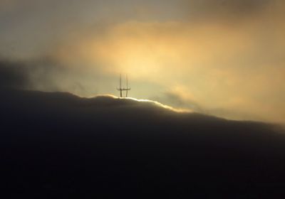 Windmills on landscape against cloudy sky