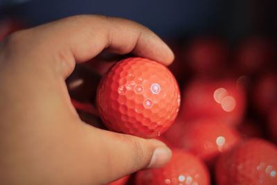 Close-up of person hand holding red golf ball