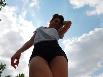 Low angle view of young woman against sky