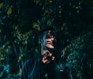 Portrait of young man standing against trees