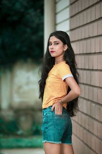 Portrait of beautiful woman standing against wall