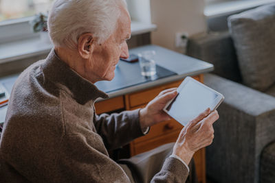 Smiling senior man using digital tablet at home