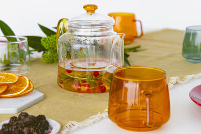 Glass teapot with tea, rosemary and berries on the table. tea/book club concept. high quality photo