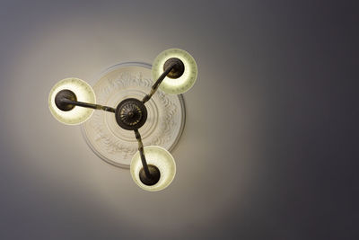 View from below on a retro style ornate metal chandelier with three lamps hanging from a ceiling.