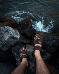 Low section of man sitting on rocky shore