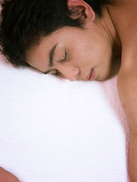 High angle view of shirtless young man sleeping on bed