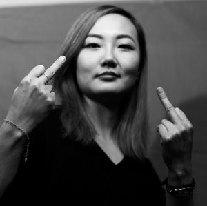 Portrait of woman showing middle finger against wall