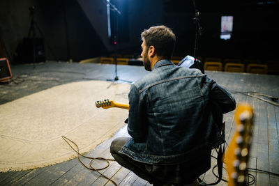 Back view of young guitarist on stage. soundcheck concept.