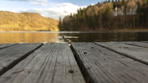 Surface level of wooden pier over lake against sky
