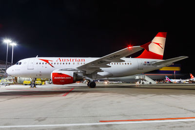 Airplane on airport runway against sky at night