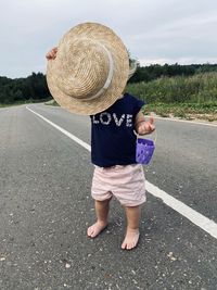 Toddler hides her face behind sun hat
