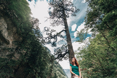 People standing amidst trees in forest against sky