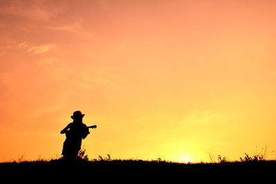 Woman playing guitar at sunset