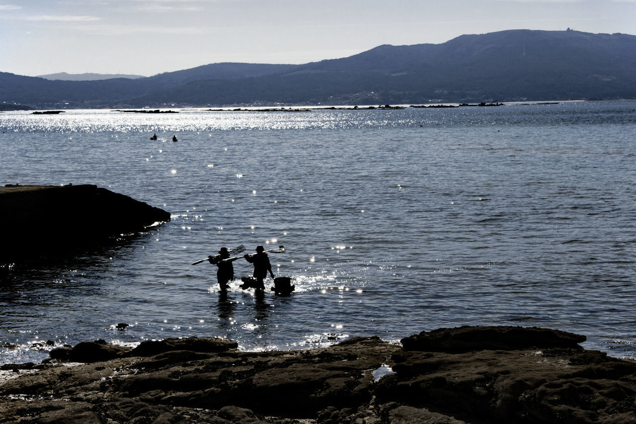 GROUP OF PEOPLE ON ROCKS AT BEACH