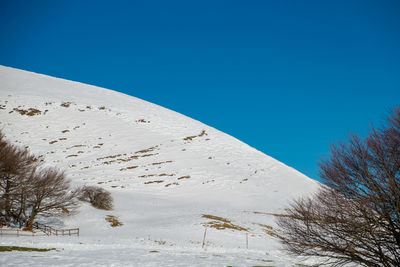 Scenic view of snow covered land against clear blue sky