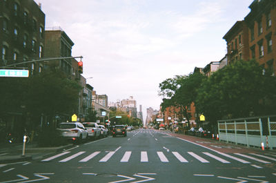 Cars on city street against sky