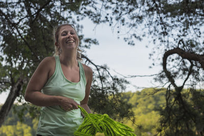 Portrait of cheerful woman holding green rope while standing great falls park