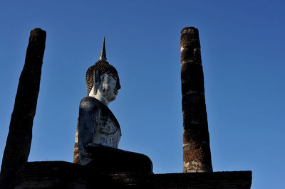 Low angle view of statue against temple building against sky