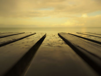 Surface level of pier against sky at sunset