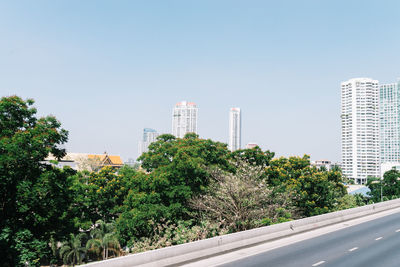 Trees in city against clear sky