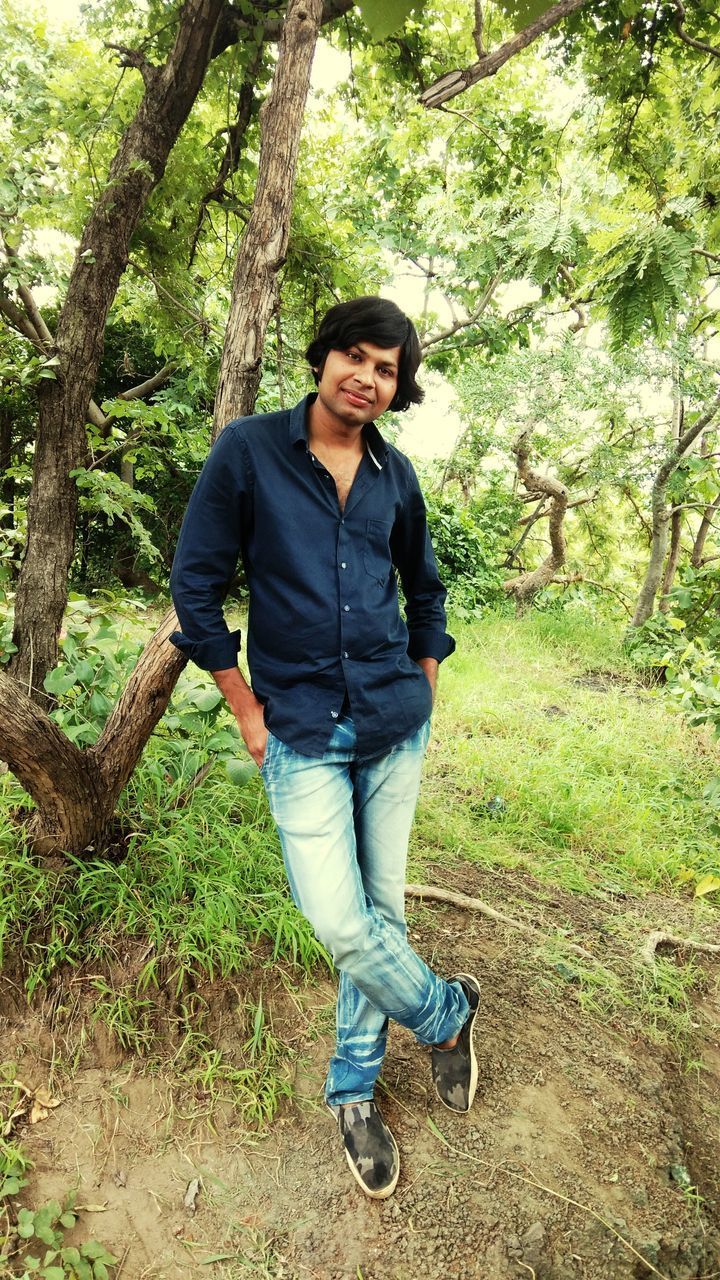 FULL LENGTH OF MAN STANDING BY TREE TRUNK