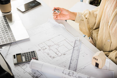 Midsection of businesswoman using calculator