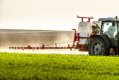 Young farmer in tractor spraying insecticide in green farm