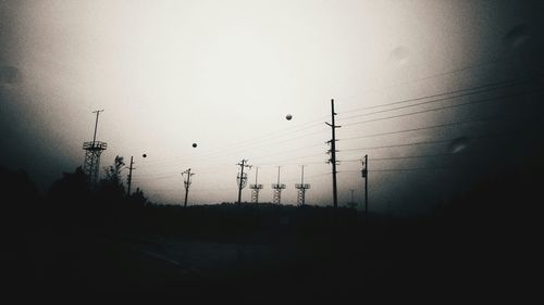 Power lines against sky at sunset