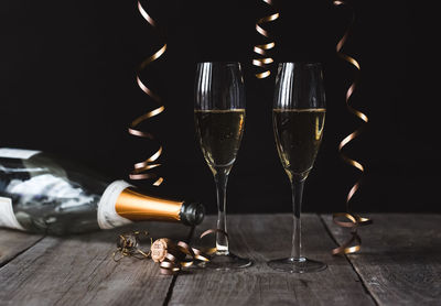 Two glasses of champagne and empty bottle with black background.