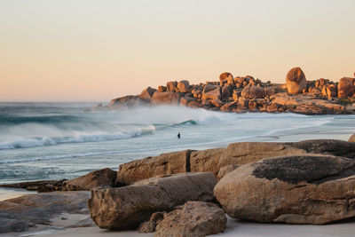 Scenic view of rocks on beach against clear sky