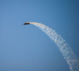 Low angle view of airplane flying against blue sky