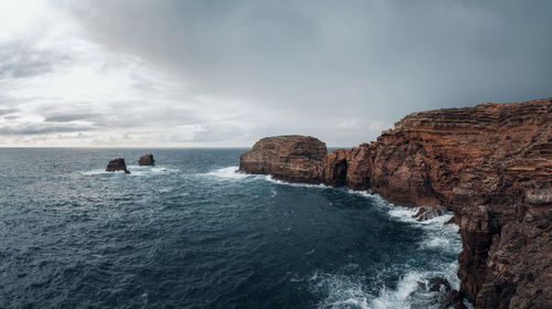 Scenic view of cliffs by sea against sky