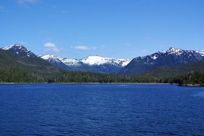 Scenic view of lake and mountains against blue sky