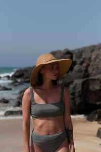 Young woman wearing hat while standing on beach