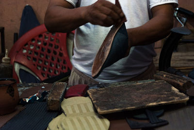 Midsection of man working on shoe in workshop