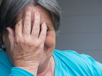 Senior adult woman covering her face with her hand