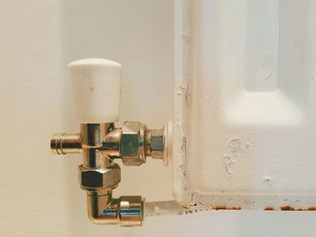 Close-up of electric lamp on table against white wall