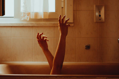 Cropped hands of woman gesturing over bathtub in bathroom