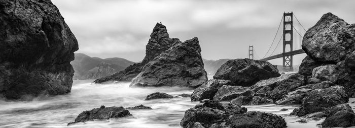 Panoramic view of rocky coastline against cloudy sky